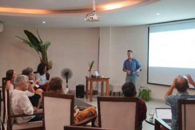 Ross presenting beside a projector screen