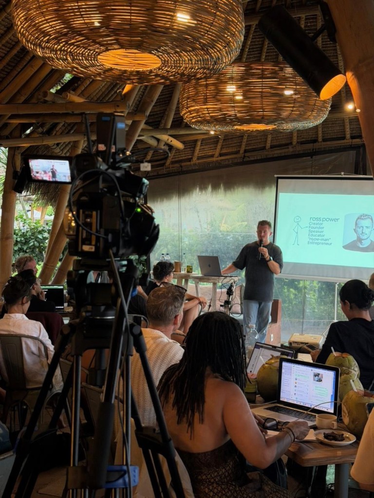 Ross speaking at an AI Powered event in a bamboo hall